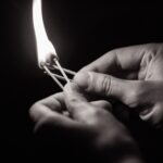 A Black and White picture of a person holding lighted matchsticks